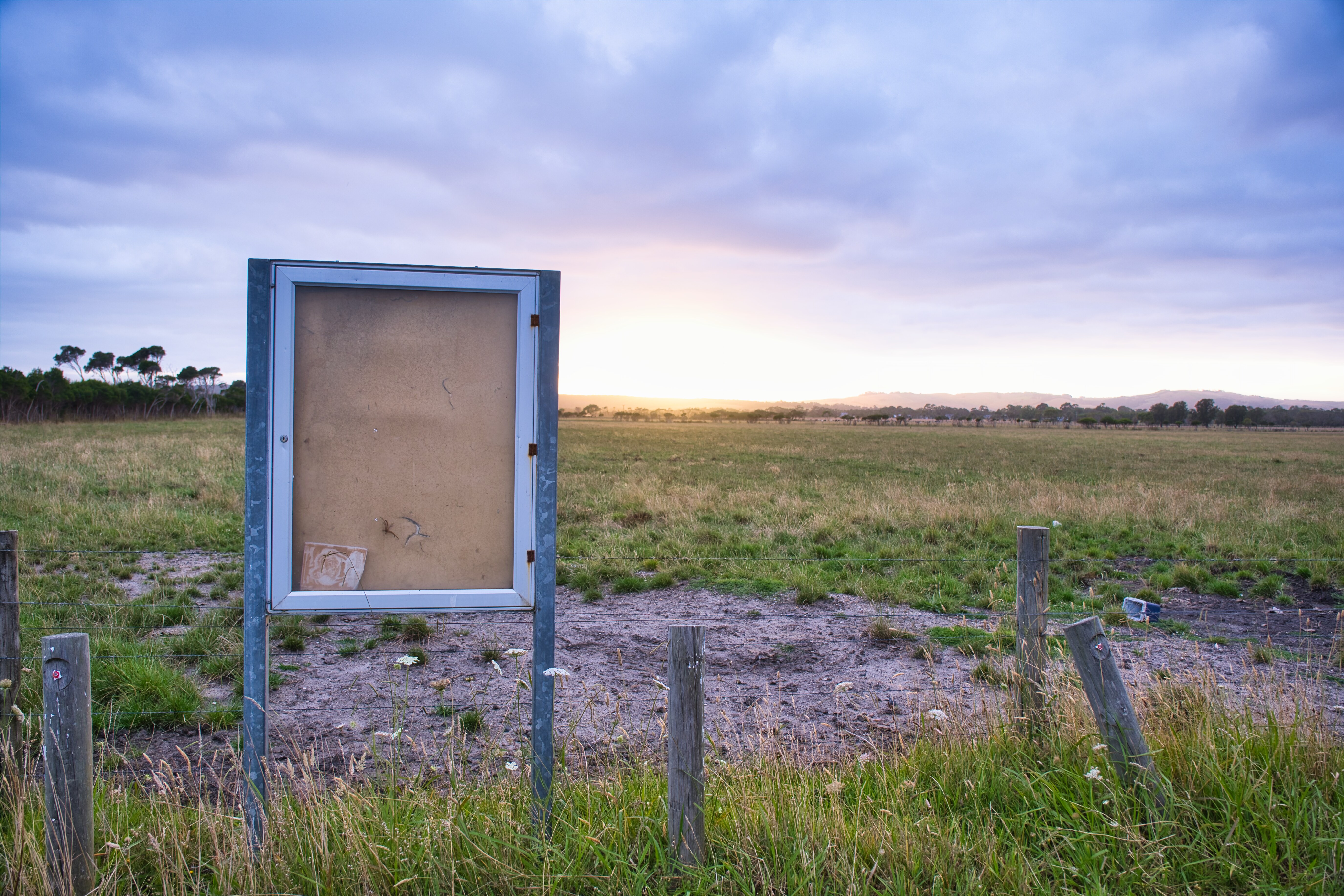 Image shows derelict land with a sunrise behind it.