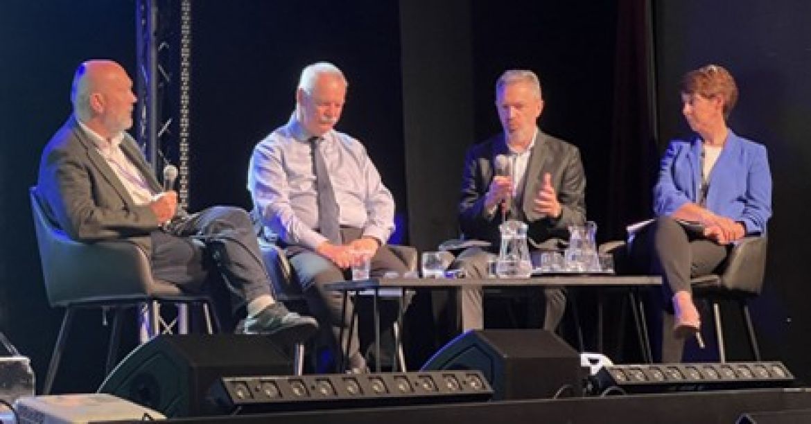 Panel speakers sitting on a stage at a conference