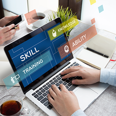 Online training concept, shows man's hands on laptop. The laptop screen displays the words skill, knowledge, training, ability.